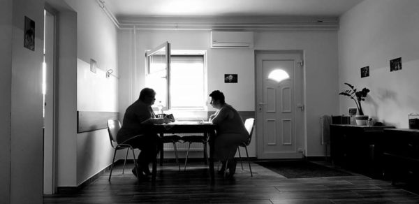 Fekete-fehér kép: A VKK központbna egy asztalnál ülő kiképző és egy hölgy épp az felékszítésről beszélgetnek