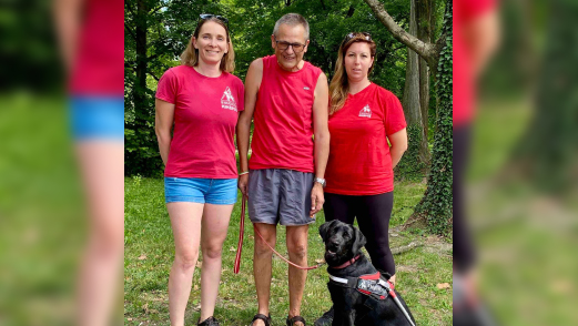 A fotón balról jobbra Végel Gabriella, Nagy János és Bajnóczy Enikő áll. Mindhárman piros pólót viselnek. Előttük Zorka ül piros MVGYOSZ-hámban, sokatmondó, okos tekintettel néz a kamerába.